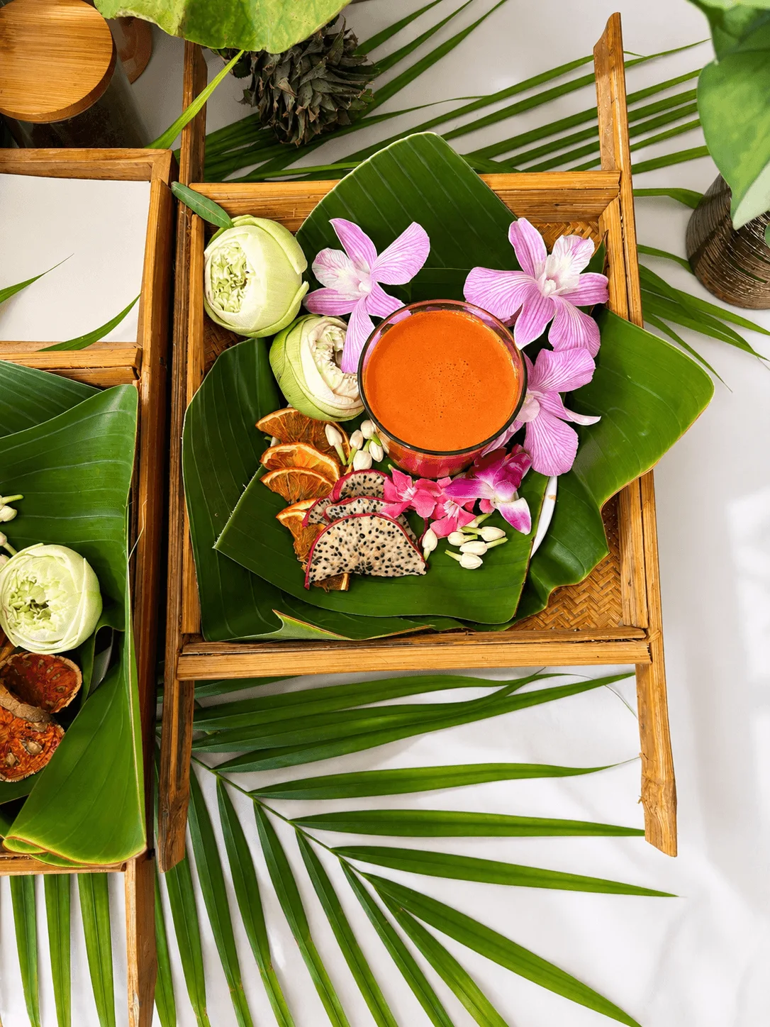 Cleanse tray overhead — red juice, orchids and dragon fruit on banana leaf