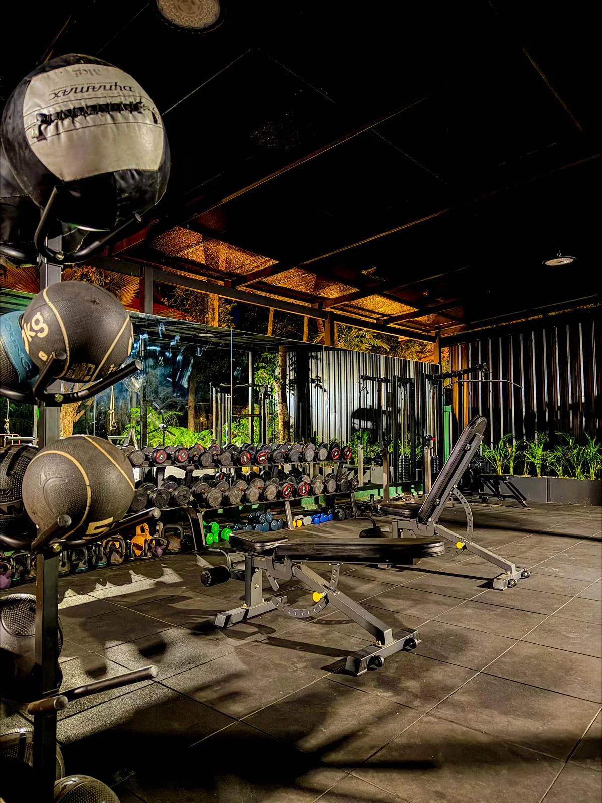 Medicine balls and dumbbell rack in the outdoor gym at Phuket Cleanse at night