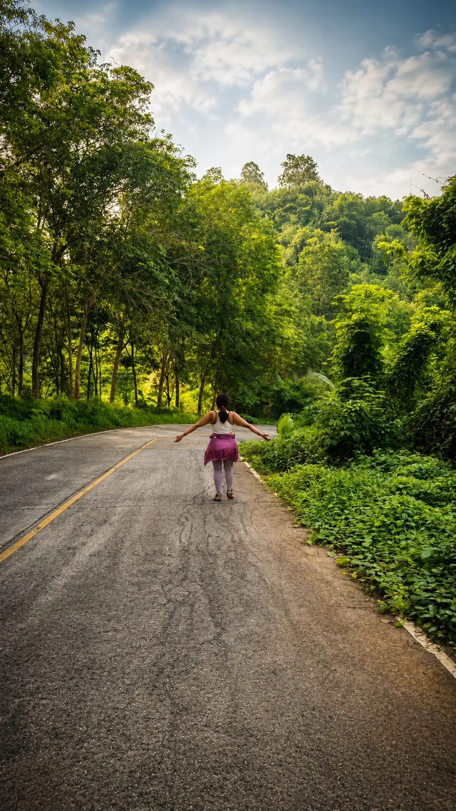 Guest walking a quiet road through the jungle near Phuket Cleanse, arms open